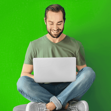 Smiling man sitting criss cross with a laptop