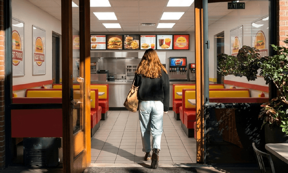 Customer walking through a branded quick-service restaurant location, representing multi-location franchise advertising with Simpli.Hub